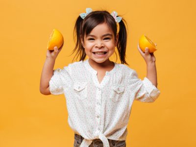 criança segurando laranjas em aula de atividades sobre alimentação saudável para educação infantil