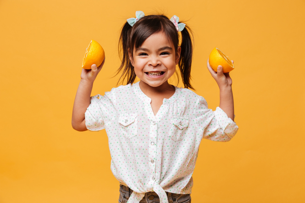 criança segurando laranjas em aula de atividades sobre alimentação saudável para educação infantil