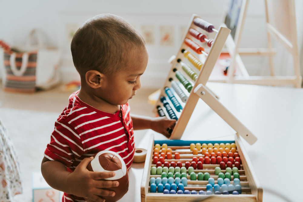 Criança brincando com ábaco colorido em ambiente de berçário.