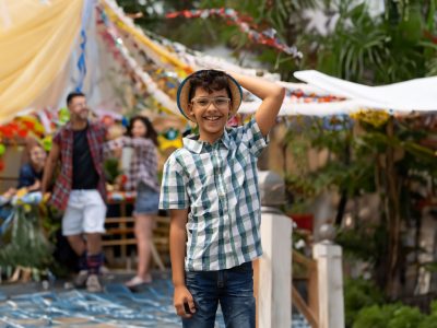 Menino sorrindo com chapéu de palha na festa junina escolar.